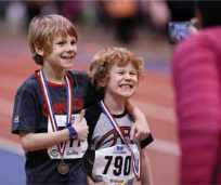 Kids smiling for a photo wearing track and field medals Kids smiling for a photo wearing track and field medals