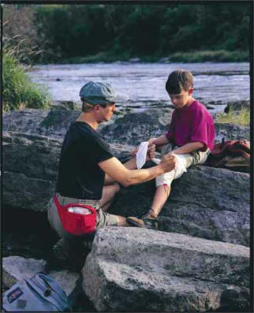 Man administering minor first aid to child on a rock Man administering minor first aid to child on a rock