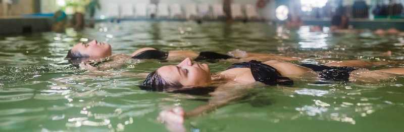 Two women floating on their back in a swimming pool in Watrous Manitou